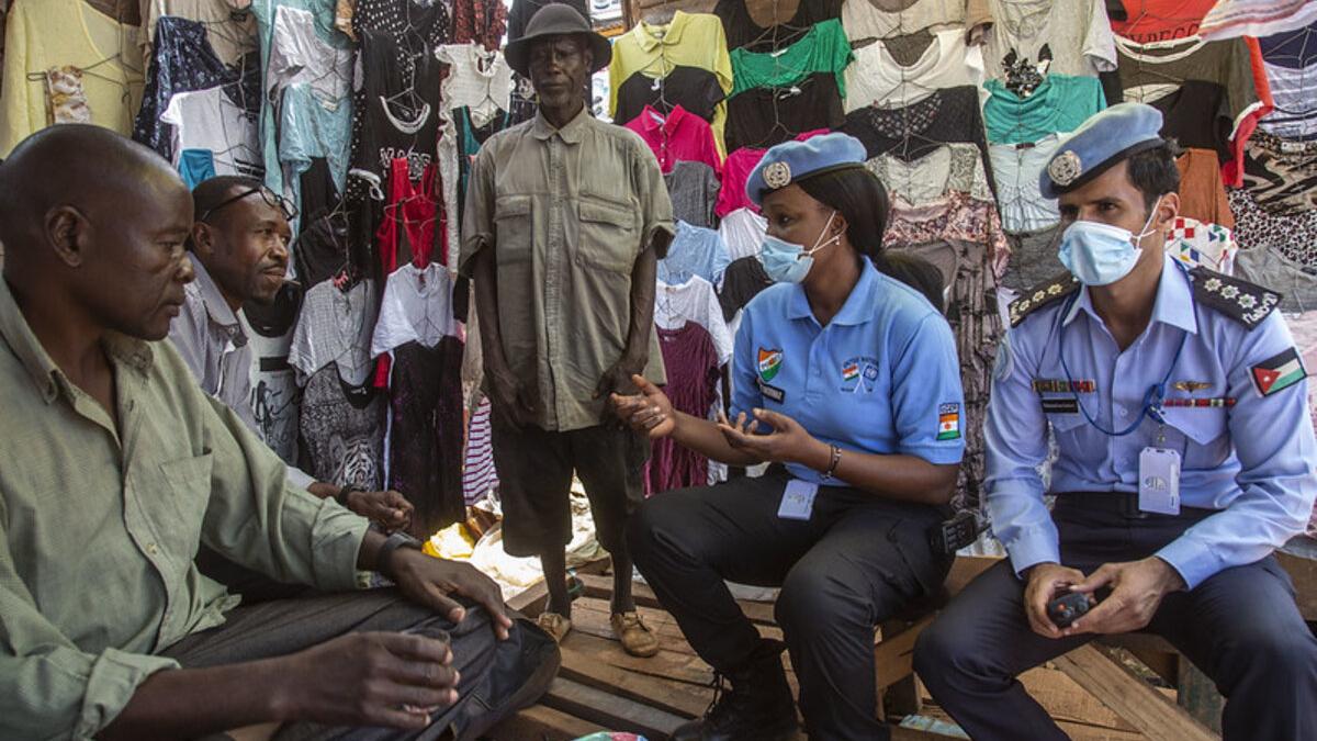 Two police officers with MINUSCA speak with community members in a t-shirt store