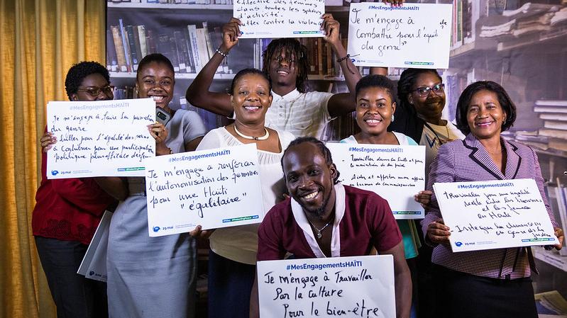 A group of people holding pieces of paper with wording on it smiling