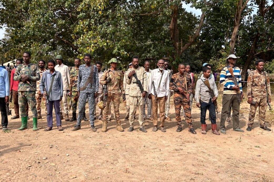 A group of amred men stand in a row
