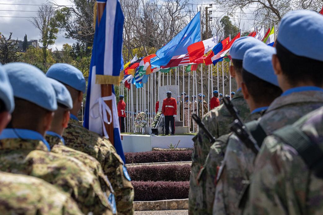 Peacekeepers stand facing a stage.