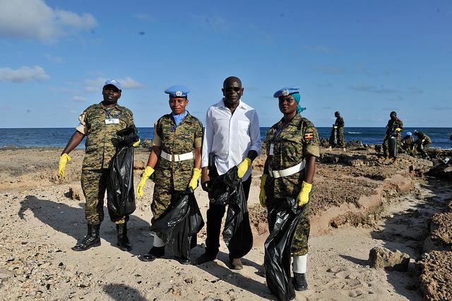 UNSOA Staff standing on a beach carrying garbage bags